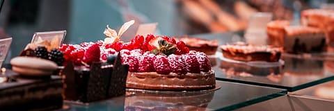 Cakes and pastries arranged in a bakery's glass display case.